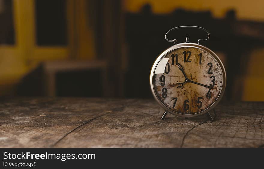 A rustic vintage alarm clock on a wood table. A rustic vintage alarm clock on a wood table.