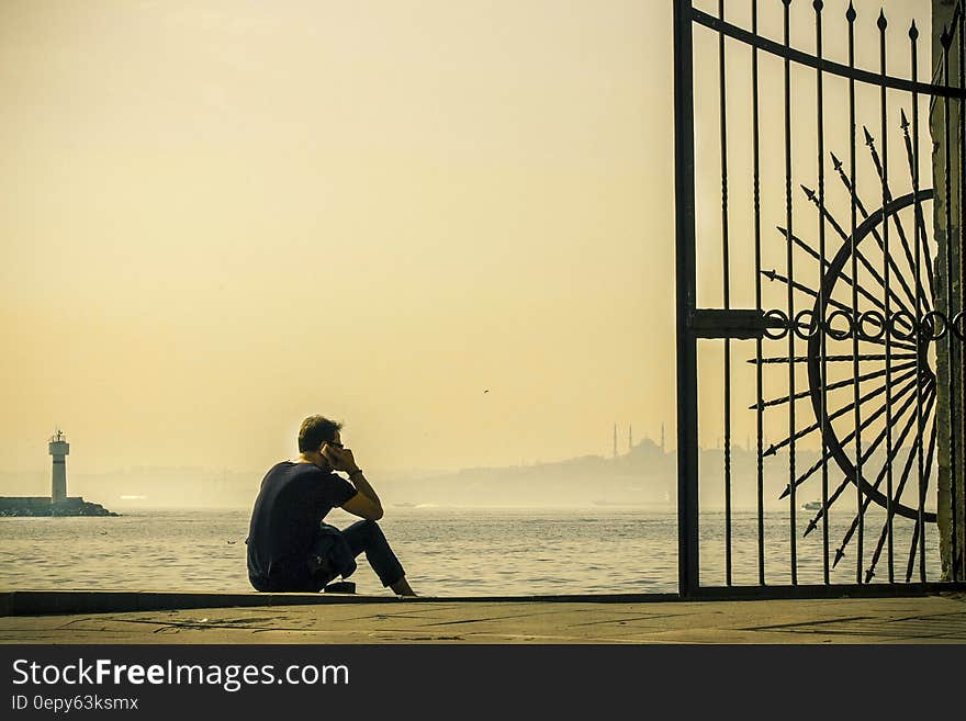 A man sitting on the pier at the harbor. A man sitting on the pier at the harbor.