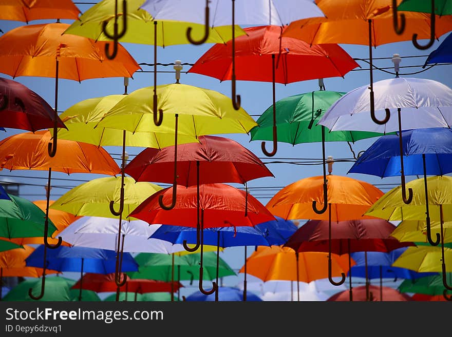 Colorful umbrellas hanging from lines on top of a street.