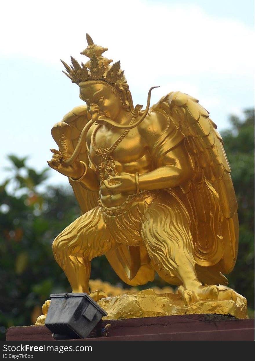 Small gild warrior statue in garden. Small gild warrior statue in garden.