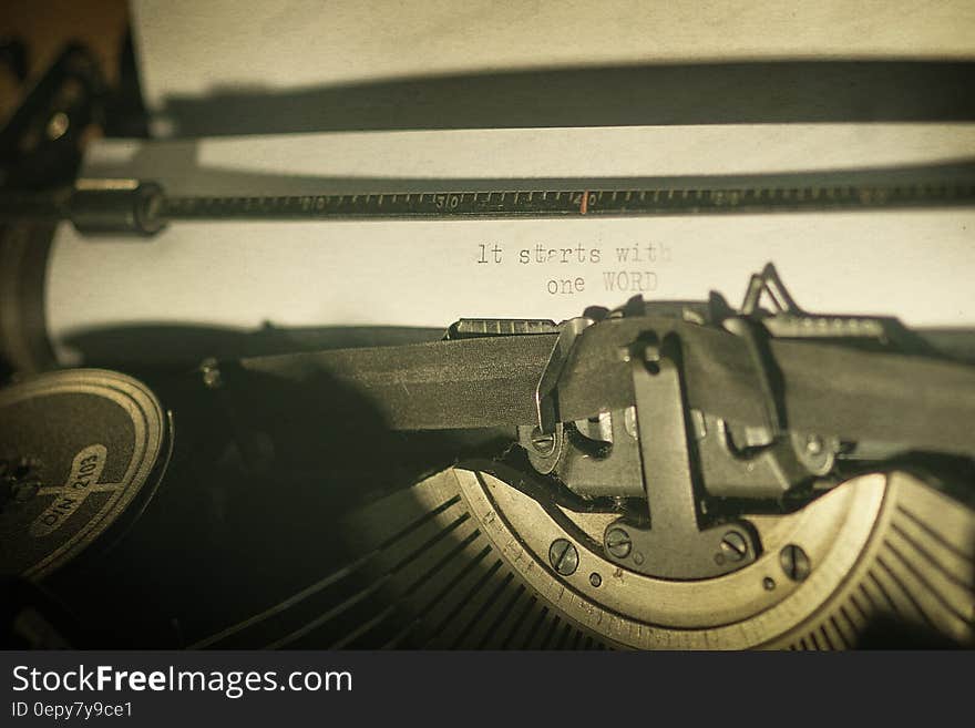 A vintage typewriter with the text "it starts with one WORD" written on a sheet.