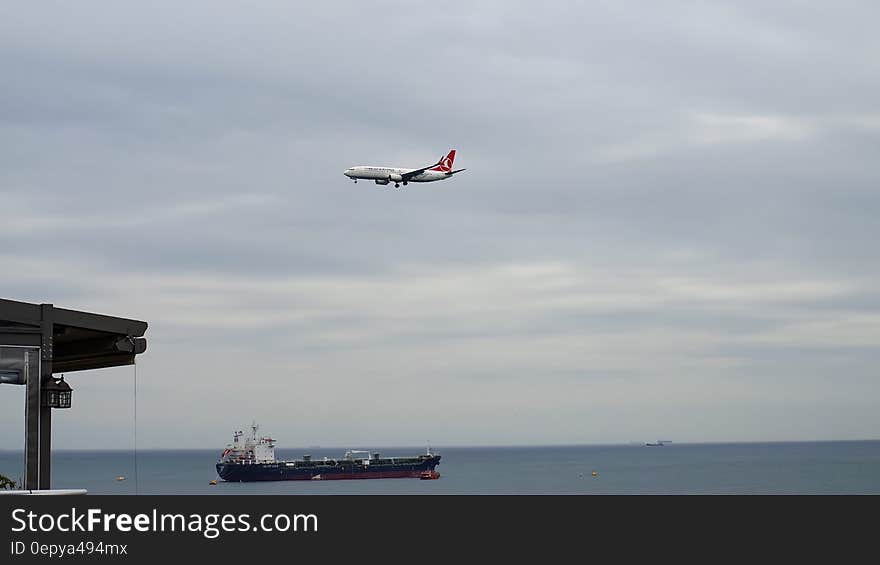 White Plane Flying Above Black Ship