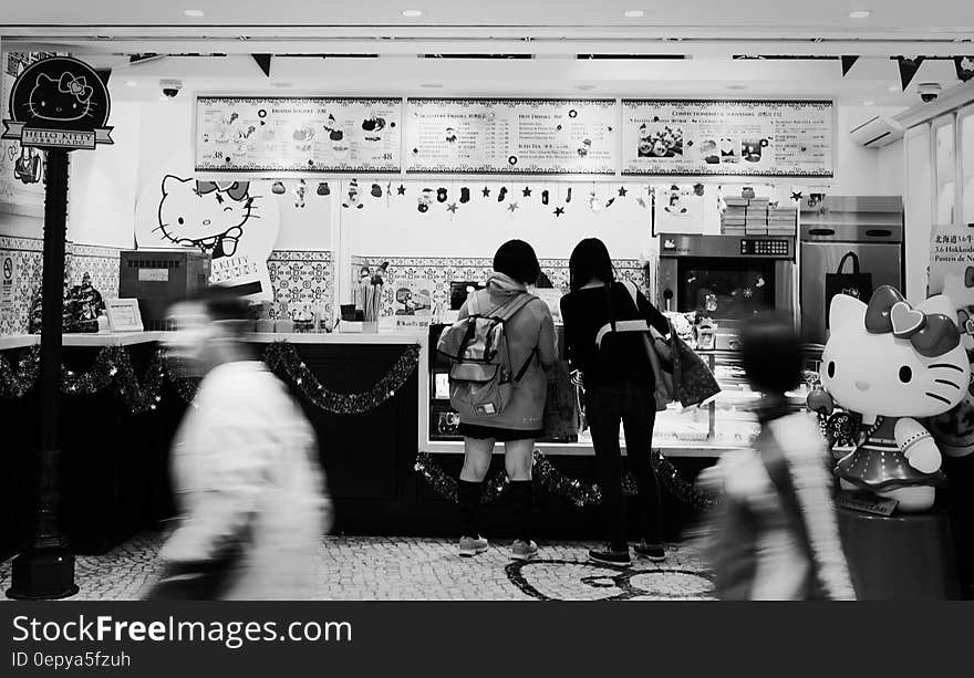 2 Women Standing Infront Hello Kitty Themed Store in Greyscale Photography