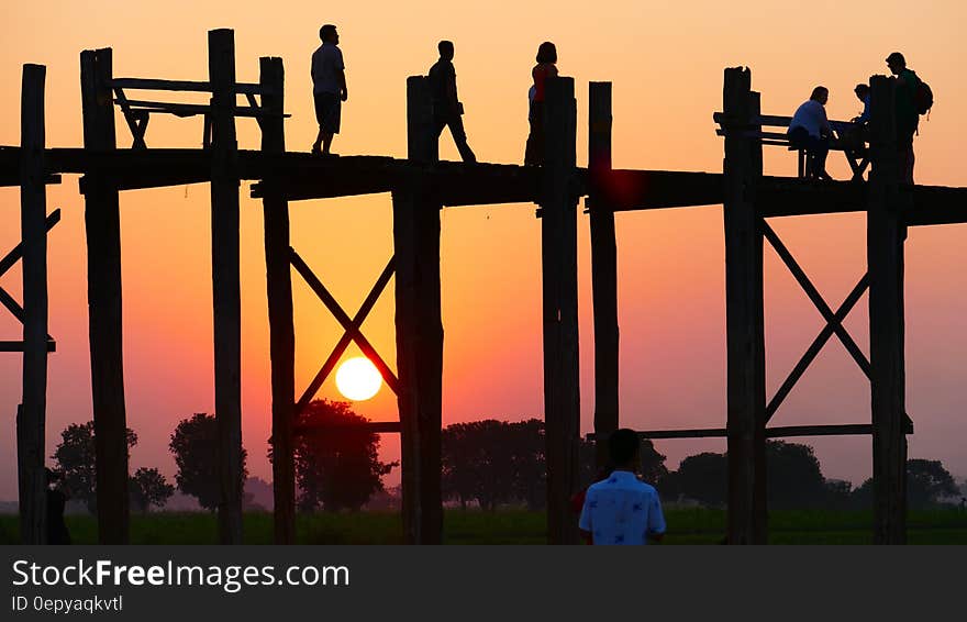 People Standing on a Bridge during Sunset .