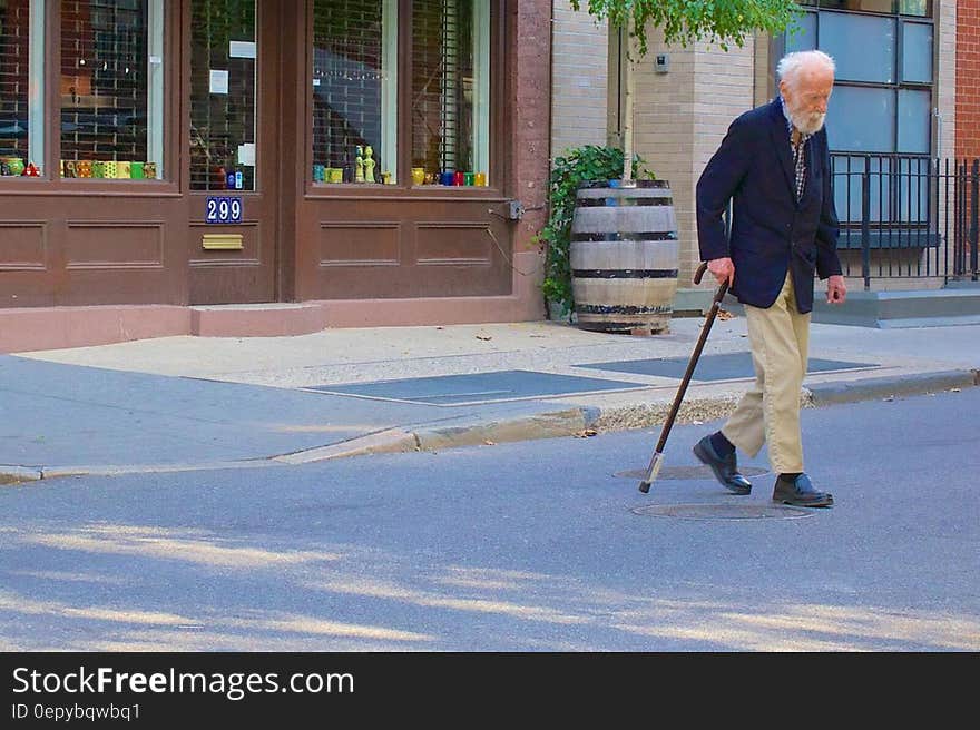 Senior man with walking stick crossing street road.