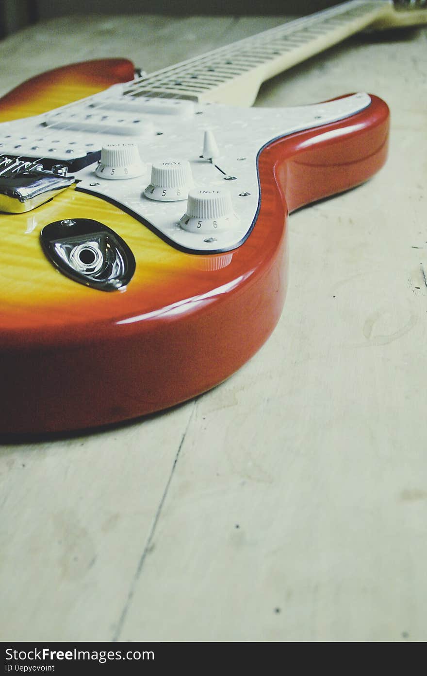 Brown and Yellow Sunburst Electric Guitar on White Tiled Flooring