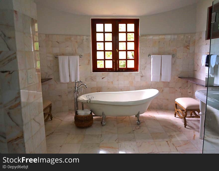 White Bathtub on White Tile Bathroom Near Brown Framed Clear Glass Window