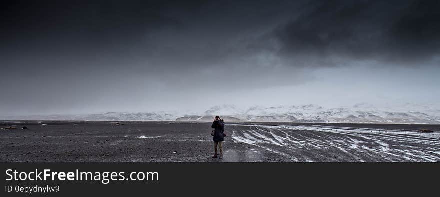 Man Standing on Gray Dessert Under Gray Cloudy Sky during Daytime