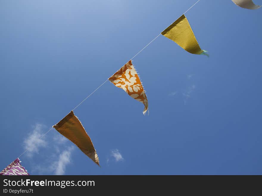 Orange Yellow and Red Flaglets Under Blue White Sky during Daytime