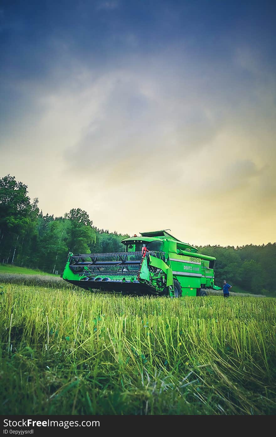 Green Harvester on Green Rice Field Under Blue and White Sky during Daytime