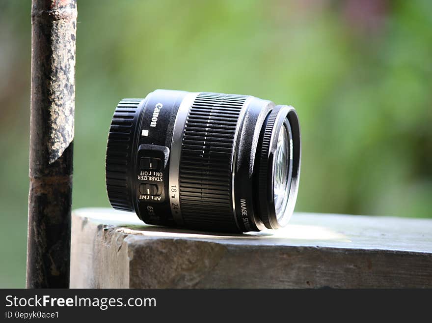 Black Canon Lens on Gray Concrete Table