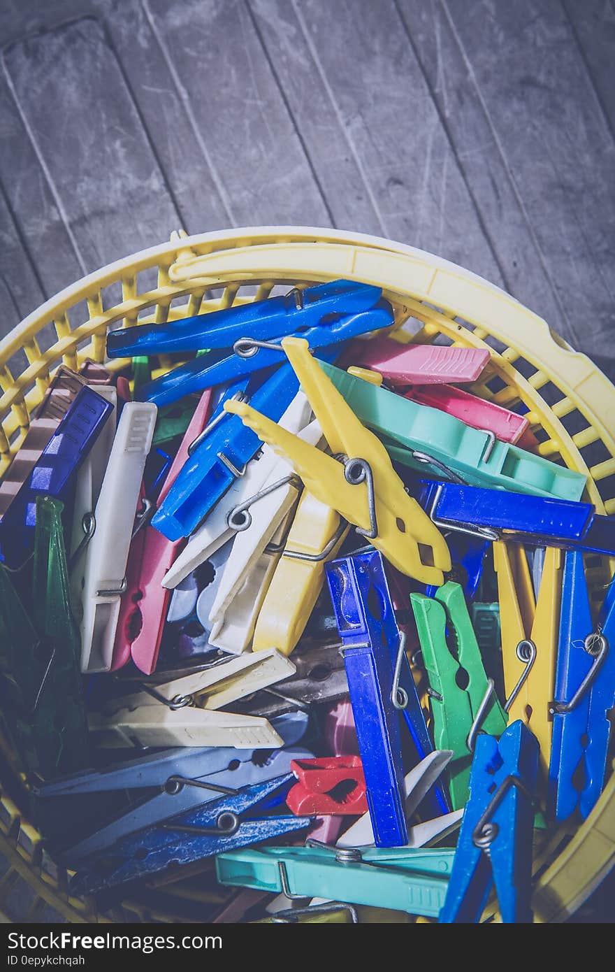 Red Blue Teal Green and Yellow Clothes Pin in Yellow Plastic Bucket