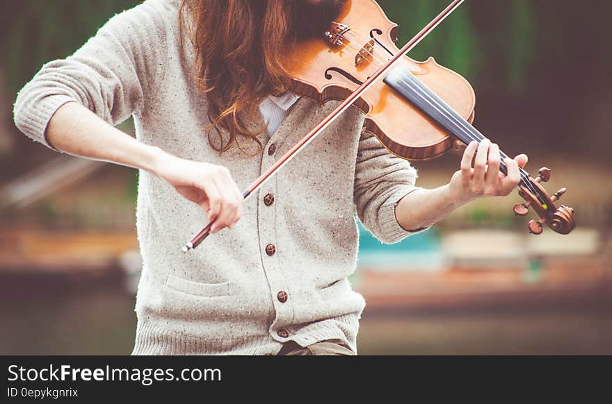 Woman in Gray Cardigan Playing a Violin during Daytime