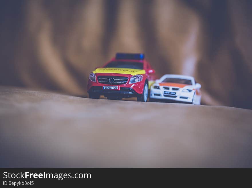 White Beside Red Toy Car on Brown Leather