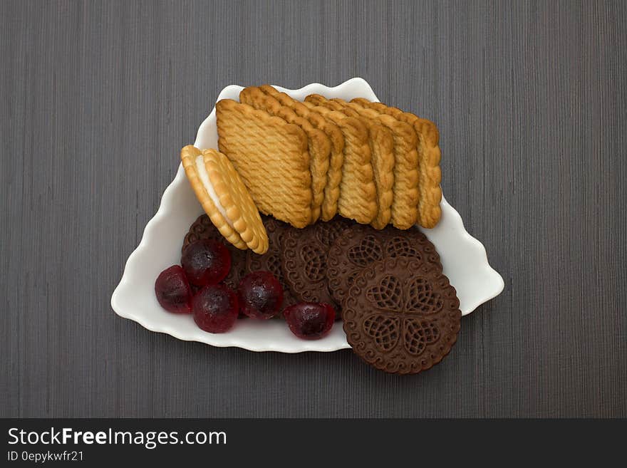 Vanilla and chocolate cookies with gumdrops on white china plate on worn planks. Vanilla and chocolate cookies with gumdrops on white china plate on worn planks.