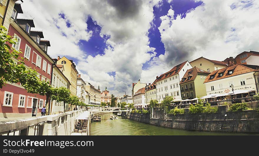 River Near Building Under White Grey and Blue Sky during Dayime