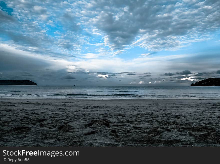 Gray Sand on Sea Shore Under Cloudy Sky during Daytime