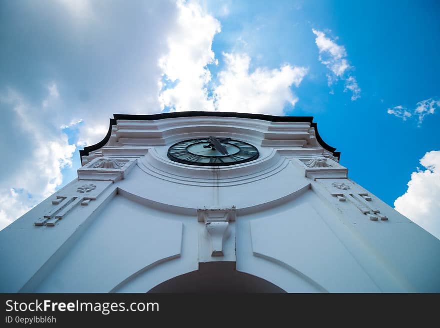 White Concrete Building With Clock Under Blue White Sky