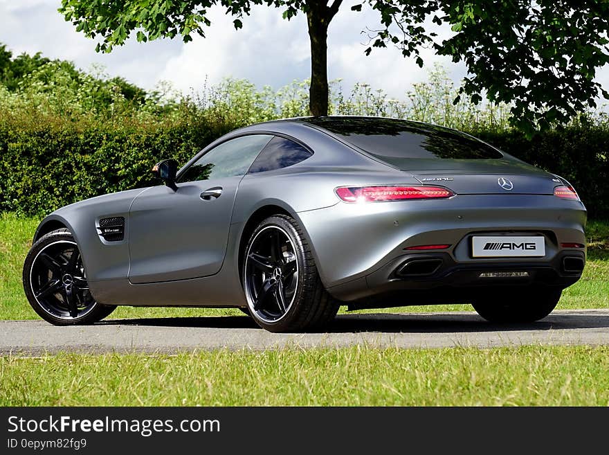 Blue Mercedes Benz luxury sports car on road in green grass on sunny day. Blue Mercedes Benz luxury sports car on road in green grass on sunny day.