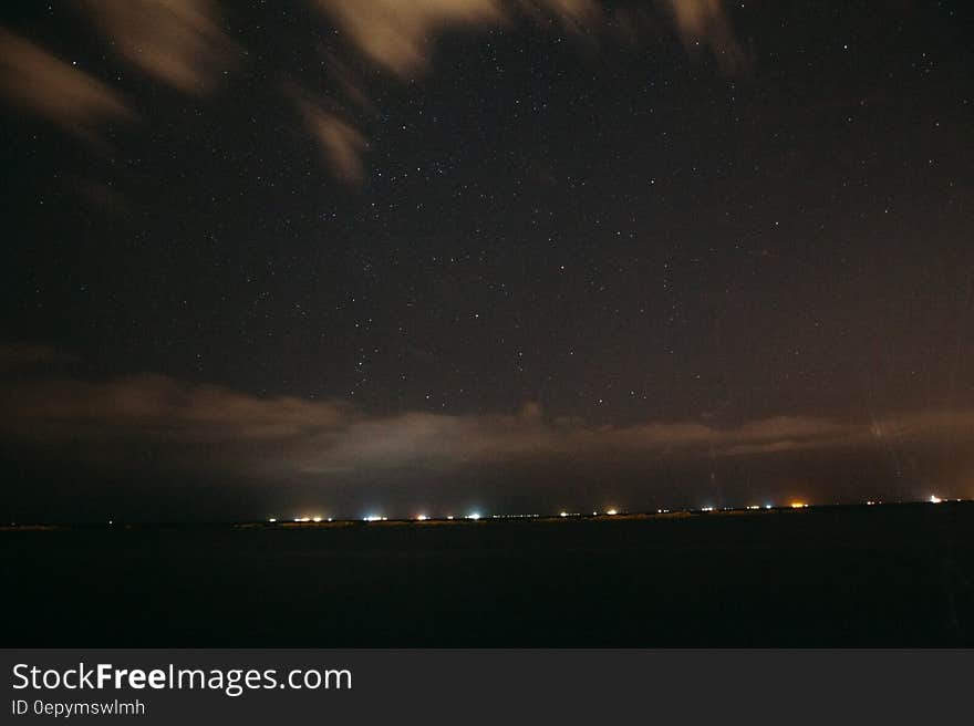 A starry sky above a landscape with city lights in the distance. A starry sky above a landscape with city lights in the distance.