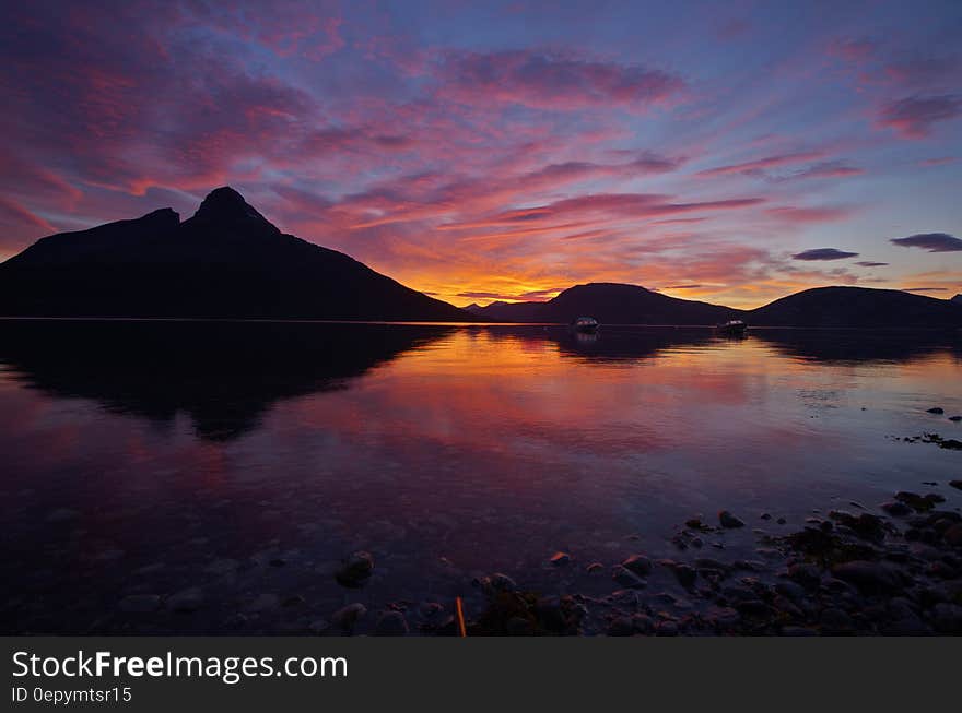 A lake with mountains in the distance with sunset skies. A lake with mountains in the distance with sunset skies.