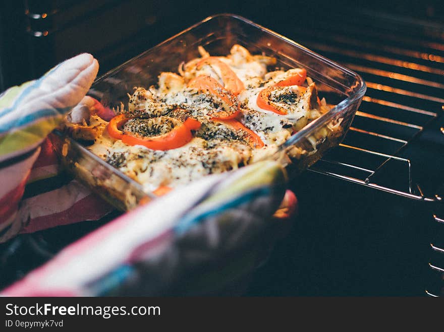 A person taking a tray of stuffed peppers out of the oven.