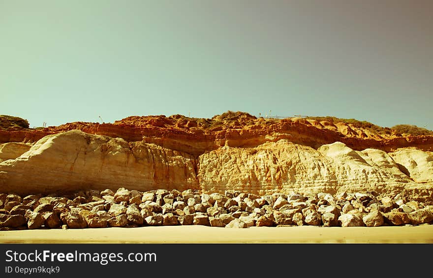 Rocks and cliff along sandy beach on sunny day. Rocks and cliff along sandy beach on sunny day.