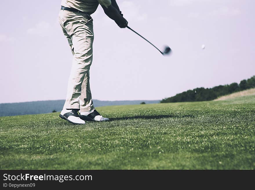 Man in White Denim Pants and Black Sandals Playing Golf during Daytime