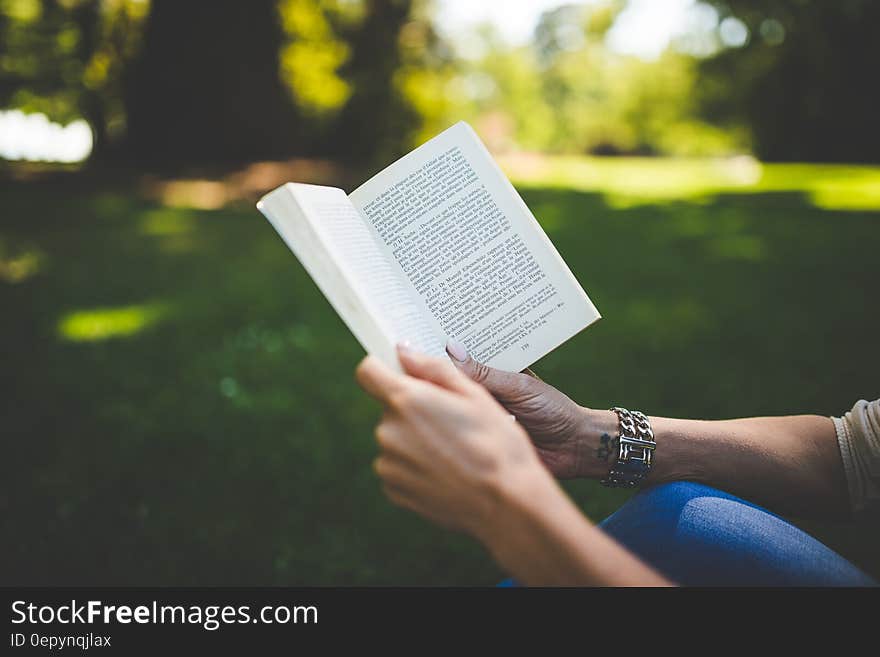 Person Holding and Reading Book during Daytime