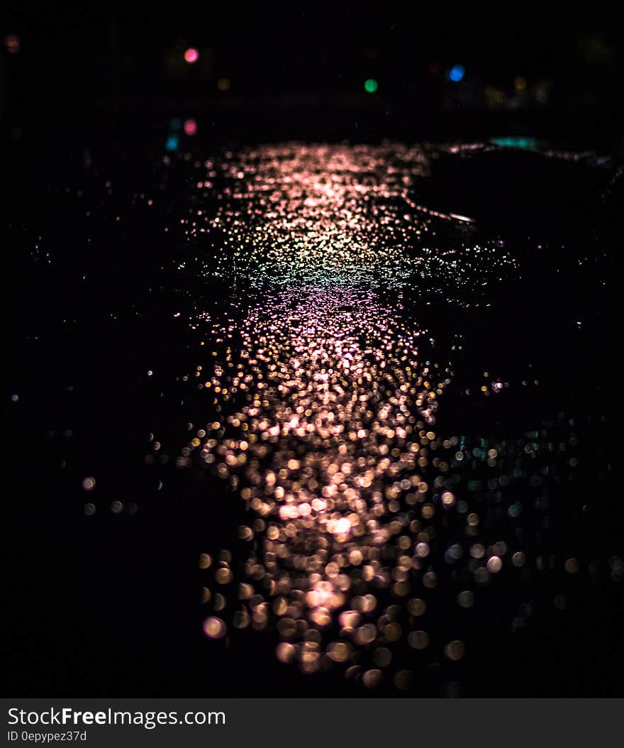 Bokeh lights reflecting on wet pavement at night.