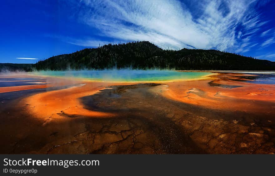 Green Forested Mountain and Hot Spring Under Blue Sky