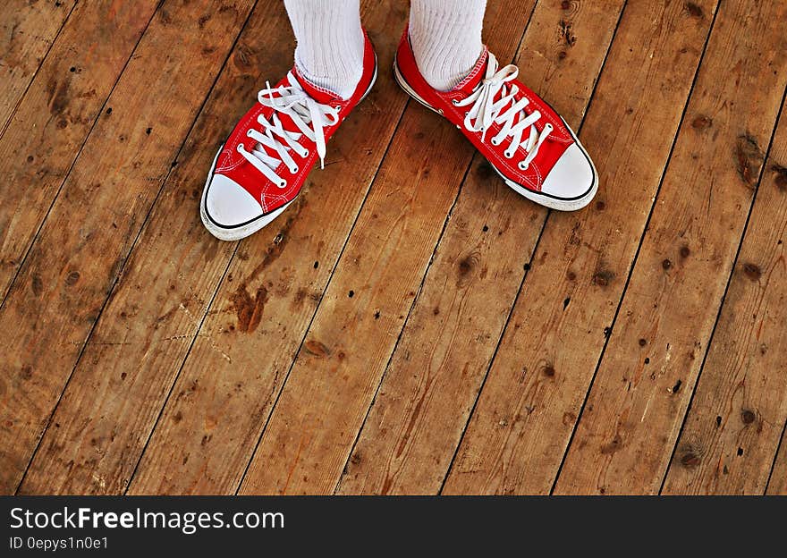 Person in Red Low Tops in Brown Wooden Floor