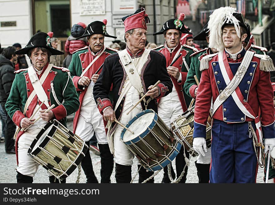 Men playing vintage drums in costumes in military recreation on streets on sunny day. Men playing vintage drums in costumes in military recreation on streets on sunny day.