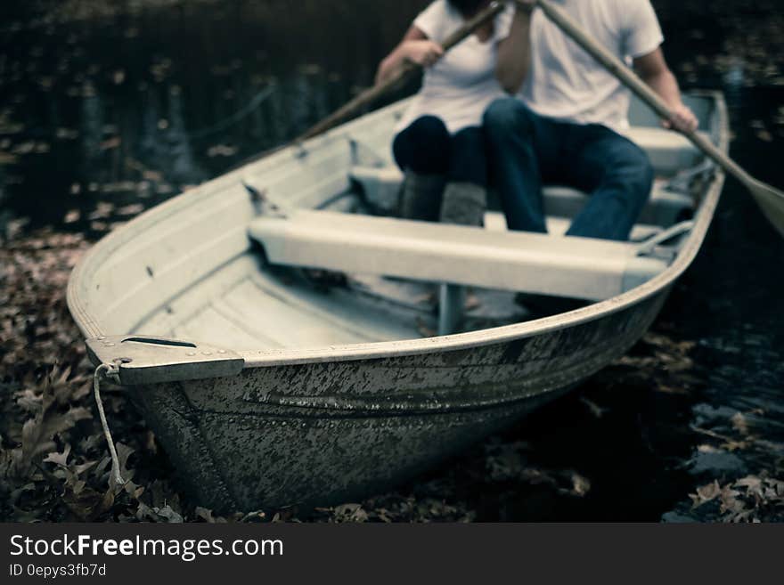 Man and Woman Sitting on Boat Holding Paddles