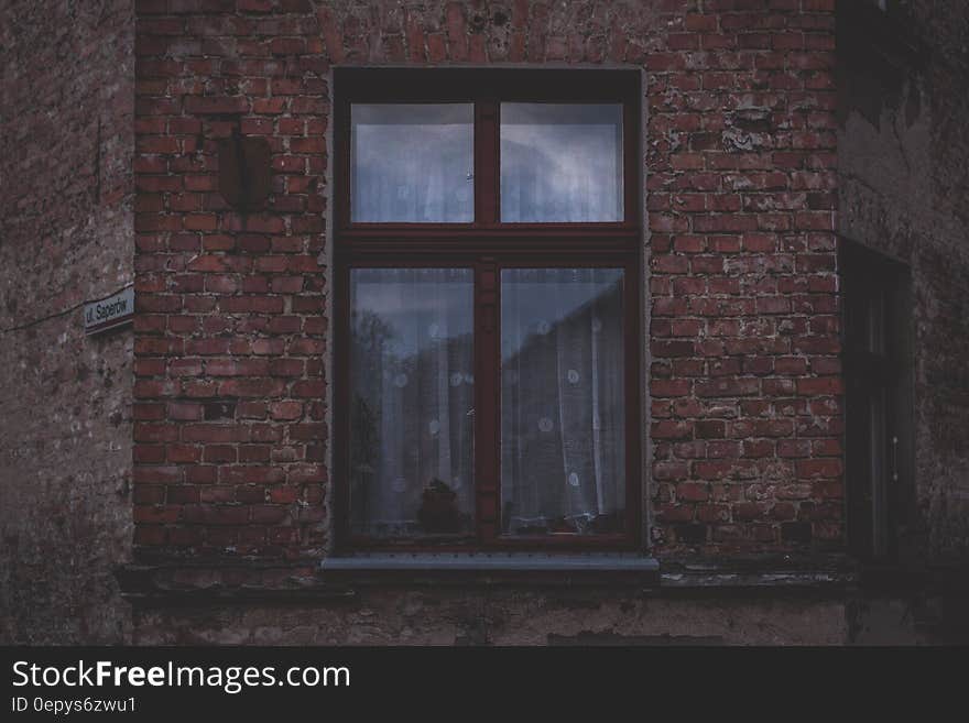 Lace curtains in window on outside brick wall. Lace curtains in window on outside brick wall.