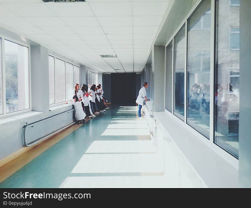 Woman in White Shirt Standing Near Glass Window Inside Room