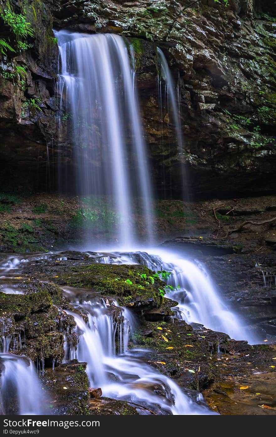 Blur of water over falls on rocky cliff in green forest. Blur of water over falls on rocky cliff in green forest.