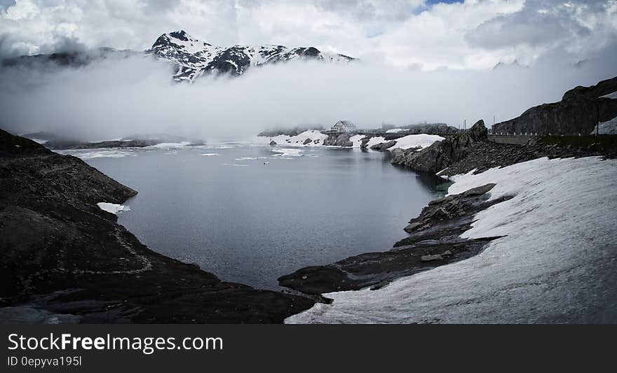 Fog in mountain peaks over lakefront on sunny day. Fog in mountain peaks over lakefront on sunny day.