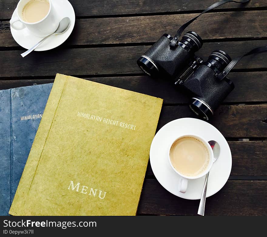 White Ceramic Tea Cup on White Saucer Near Menu Book