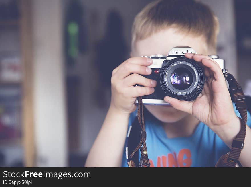 Boy in Blue Crew Neck T Shirt Taking Photo Using Minolta Dslr Camera during Daytime