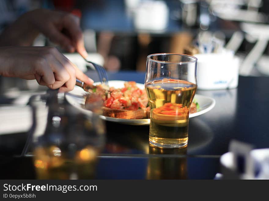 Pilsner Glass With Beer Beside White Plate