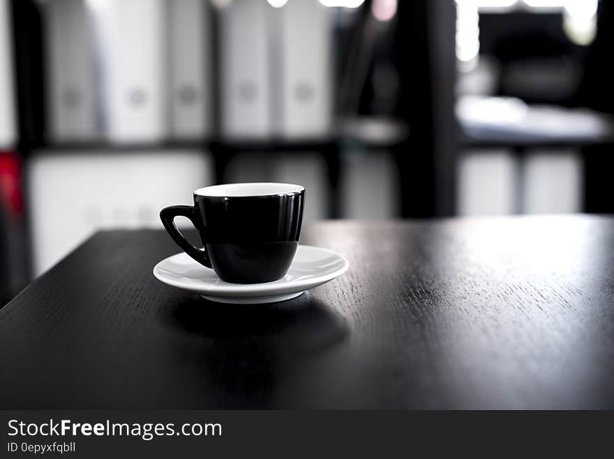 Black and White Ceramic Tea Cup With Saucer on Black Wooden Table