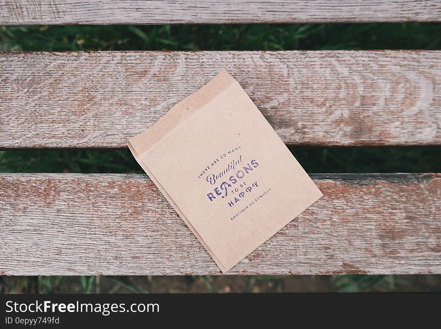 A close up of a paper with message reasons to be happy on a bench. A close up of a paper with message reasons to be happy on a bench.