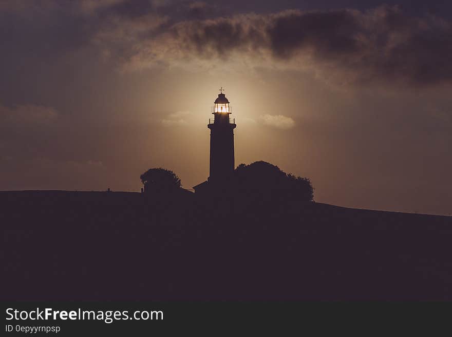 Silhouette of Light House Under Gray Dark Sky