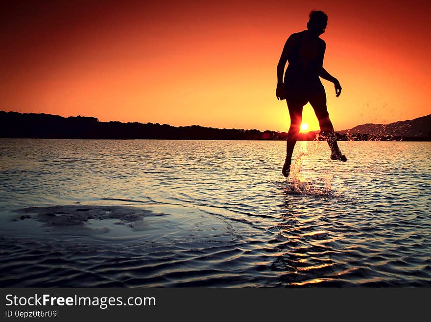 Silhouette of person jumping into water at sunset. Silhouette of person jumping into water at sunset.