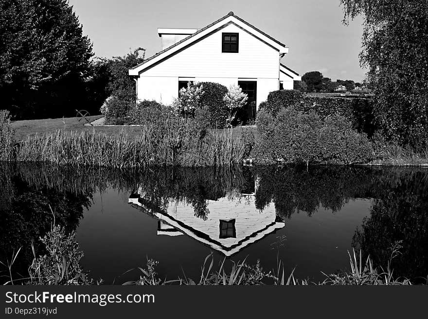 Exterior of white house reflecting in water in black and white.