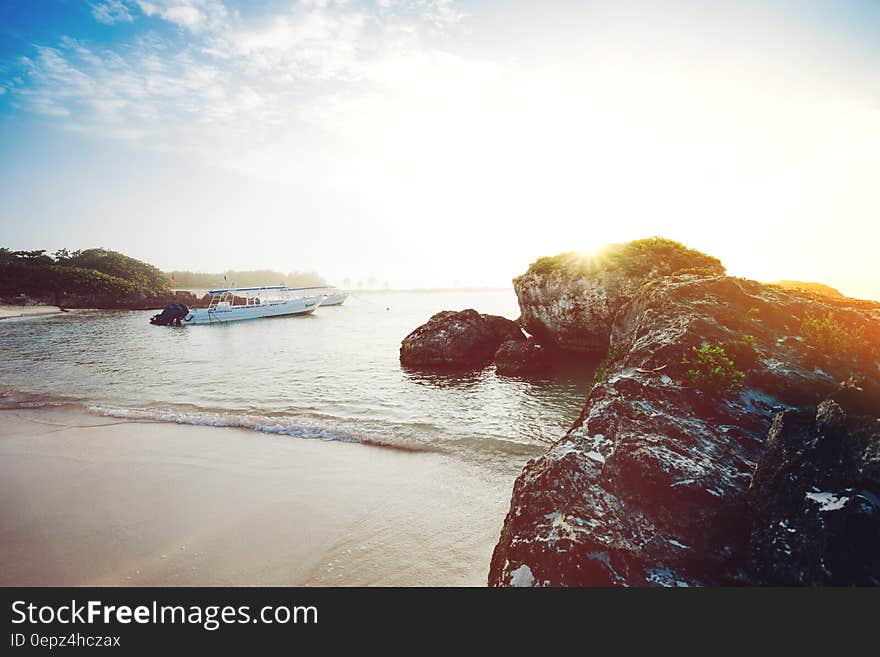 Boat anchored offshore along rocks on sandy coastline on sunny day in Mexico. Boat anchored offshore along rocks on sandy coastline on sunny day in Mexico.