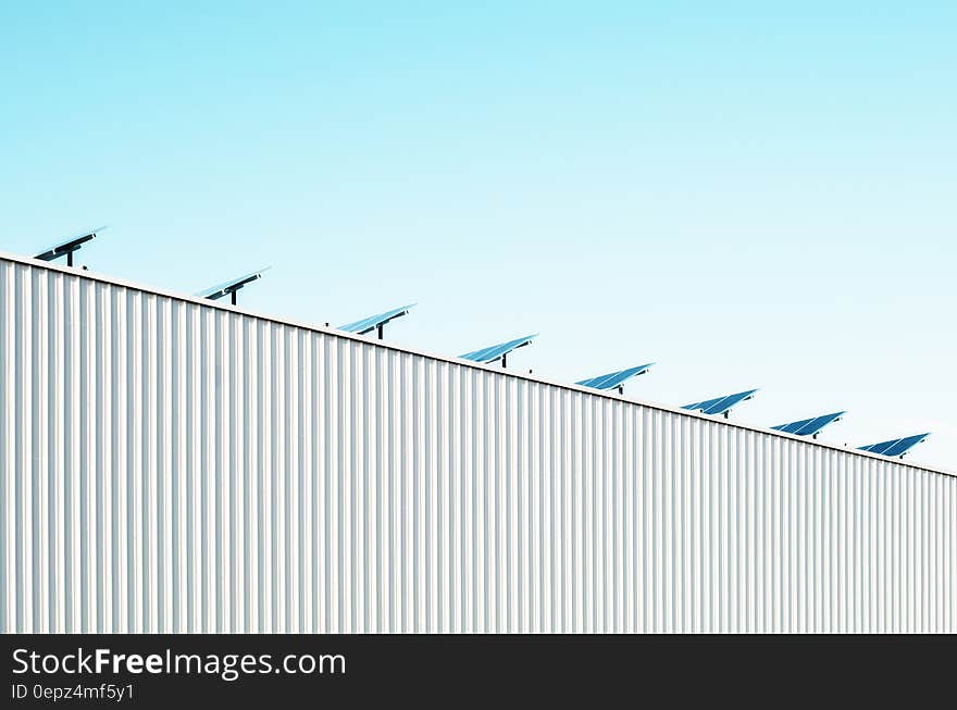 Solar panels on rooftop of corrugated metal building against blue skies on sunny day. Solar panels on rooftop of corrugated metal building against blue skies on sunny day.