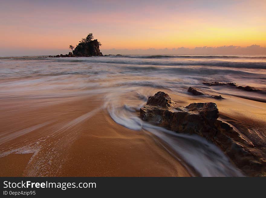 Rocks in waves along sandy beach at sunset. Rocks in waves along sandy beach at sunset.