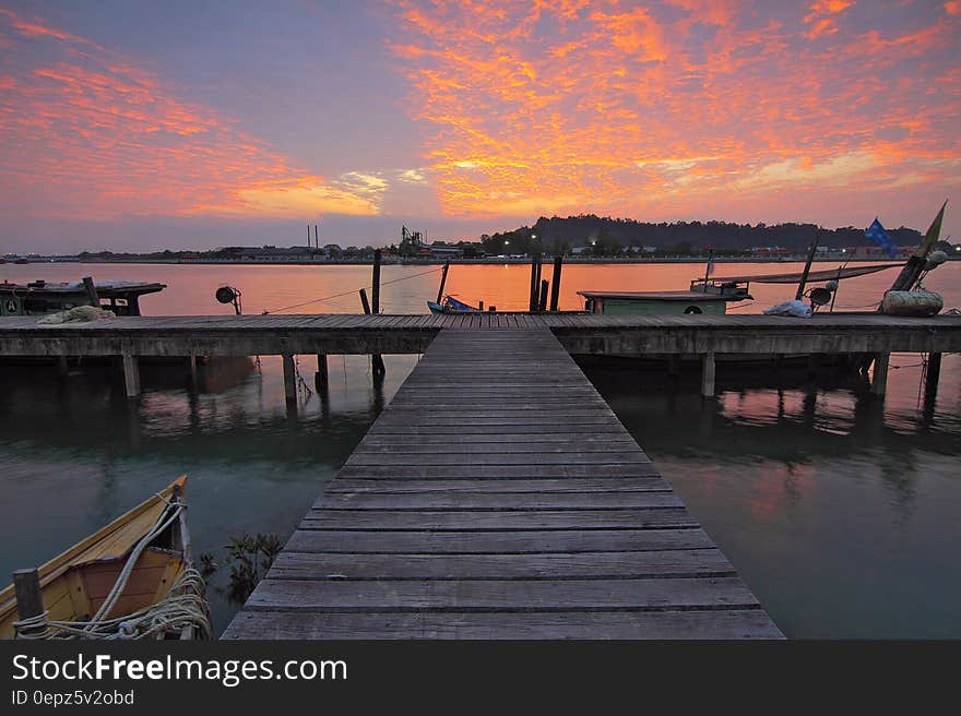 A wood jetty with boats at sunset. A wood jetty with boats at sunset.